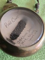 close-up of fossil pinecone inside brass case showing handwritten label