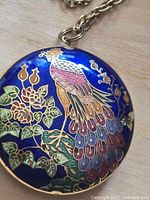Close-up of cloisonné-style peacock pendant detail