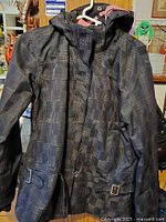 Front view of plaid ski jacket on hanger