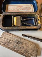 Open Rolls Razor case showing razor, hone/strop, handle and instruction sheet; second case lid and hone visible