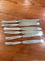 Six Birks dinner knives laid out on wooden surface