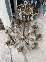 full view of chandelier showing eight arms, leaf motifs, crystal prisms, bulbs