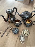 Full lot showing coffee pot, teapot, sugar, creamer, lidded container, flatware, brass strainer set