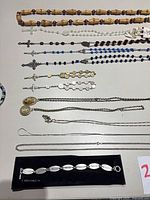 Overview of rosaries, chains and bracelet laid out on table