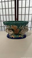 Front view of multicolor glazed ceramic pedestal compote showing elephant and foliage relief