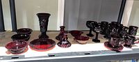 Full lot view showing all ruby red pressed glass pieces on shelf