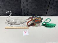 All three glass swan pieces side by side with ruler for scale