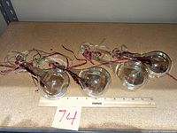 Four iridescent teardrop ornaments laid beside ruler