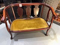 Front view of mahogany settee showing back splats, arms, velvet seat