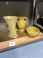 Group view of three yellow pottery pieces on shelf