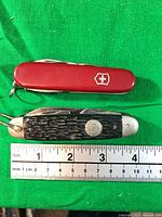 Closed Swiss Army and PAL knives next to ruler