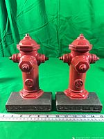 Front view of both red cast iron fire hydrant bookends on bases reading SENTINEL
