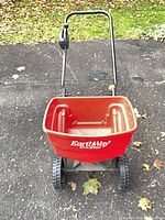 Front view of EarthWay red hopper spreader with handle and wheels