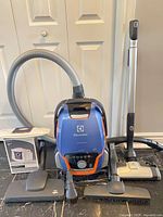 Full lot showing canister vacuum, hose, wand, power head, three smaller attachments, and box of bags