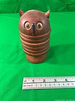 Front view of assembled wooden owl coaster holder next to ruler