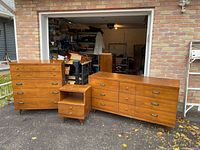 Three-piece bedroom set displayed in driveway: long dresser, tall chest, nightstand