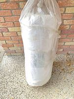 Full view of sealed roll of insulation leaning against brick wall