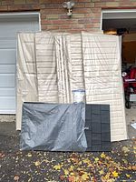 Stacked beige vinyl panels, black roof pieces in front