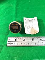 Front view showing LCD display, bezel, instruction leaflet, ruler for scale