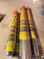 Seven yellow-wrapped rolls of Weed Block fabric on floor