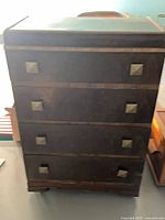 Front view showing four drawers, veneer banding, pyramid pulls, waterfall top