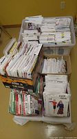 Two plastic totes and boxes filled with upright sewing pattern envelopes