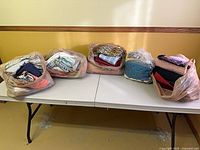 Five grocery bags filled with folded fabric pieces on table