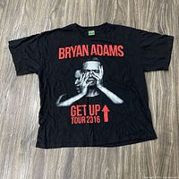 Front view of Bryan Adams Get Up Tour 2016 black T-shirt laid flat
