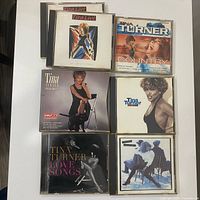 Six CD cases laid out showing album covers including Love Songs, Simply The Best, Foreign Affair, Sings Country, Break Every Rule, plus one additional case behind