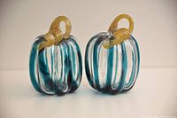 Front view of both teal striped glass pumpkins showing stems and striping
