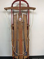 Front view of wooden sled showing graphics and rope