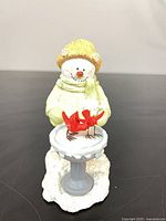 Front view of snowman figurine with birdbath and cardinal