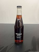 Front view of sealed Shinola Cola 12 oz glass bottle