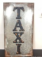 Front of galvanized panel showing TAXI letters and frame