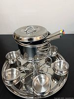 complete fondue set assembled showing pot on stand, tray with bowls, forks, lid