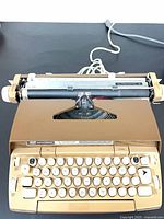 Top view of typewriter showing keyboard, carriage, power cord