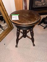 Full view of piano stool, showing seat, turned legs, claw feet