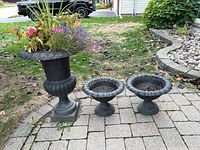 Large pedestal urn with plants and two smaller urns on patio