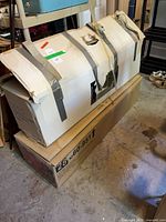 Two cardboard boxes containing artificial Christmas trees stacked in storage area