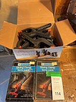 Box containing spring clamps and two packaged Mastercraft gluing clamp fixtures