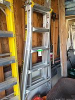 Full view of folded Stanley aluminum combination ladder leaning against wall