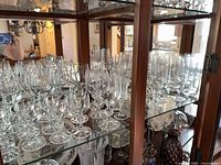 Cabinet shelves filled with assorted crystal stemware, showing quantity and variety