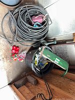 Lot overview showing coiled soaker hose, feeders, watering cans, bucket with tools