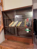 Front view of bookcase with sliding glass doors showing interior shelf and drawers