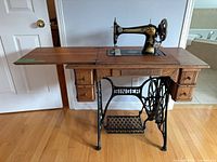 Full view of Singer treadle machine with cabinet and leaf extended