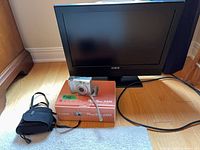 Aveis flat screen TV, Canon camera on box, camera case and cords