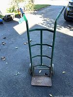 Front view of green steel hand truck with two wheels and rusted toe plate
