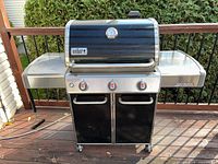 Front view of Weber Genesis Special Edition grill showing three control knobs, black enamel lid, stainless steel shelves