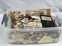 Overall view of clear plastic bin filled with loose stamps and stamp folio
