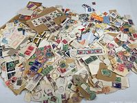 Large pile of unsorted canceled stamps on paper and loose